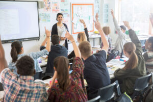 teens raising hands in classroom